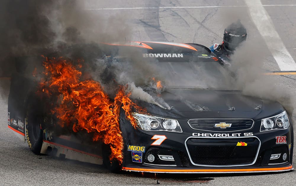 Alex Bowman climbs out of his burning car during the NASCAR Sprint Cup series auto race at New Hampshire Motor Speedway in Loudon, N.H. 