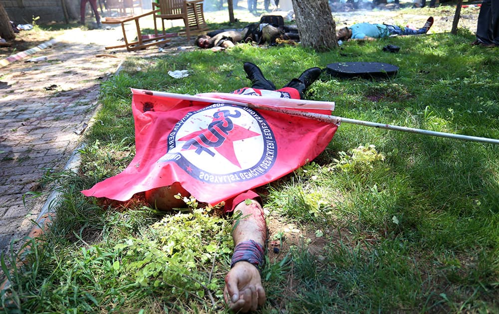 Bodies lie on the ground with one being covered with a Federation of the Socialist Youth Associations flag, after an explosion, in the southeastern Turkish city of Suruc near the Syrian border, Turkey. An explosion Monday killed at least 10 people and injured scores of others in the southeastern Turkish city of Suruc near the Syrian border, state-run Turkish news agencies reported.