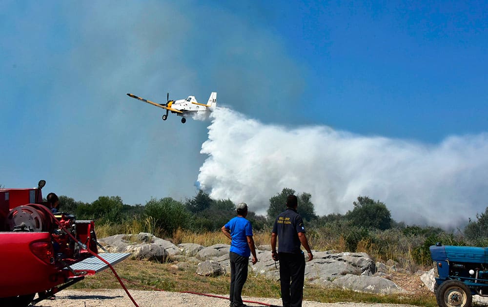 A small airplane drops water over the fire at the holiday resort village of Asini, near the town of Nafplio, about 140km (87 miles) southwest of Athens.