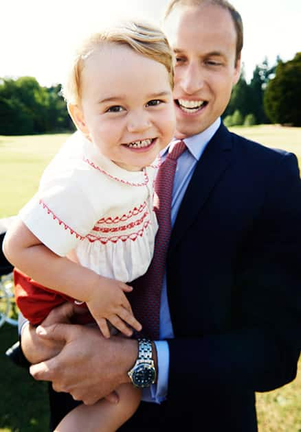 This image released by Kensington Palace, Britain's Prince William holds his son Prince George following the christening of Princess Charlotte, in the grounds of Sandringham House, England.