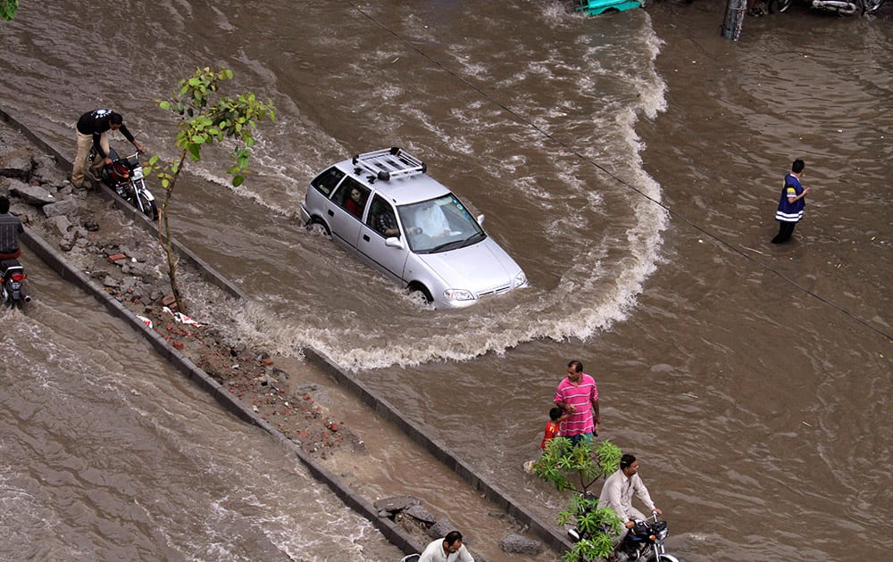 A car drives through a flooded road caused by heavy rains in Lahore, Pakistan.