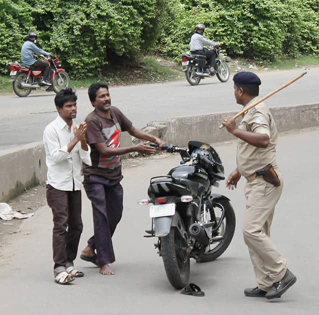 A police man in action against two men who tried to create disturbance in riot hit Mango in Jamshedpur.