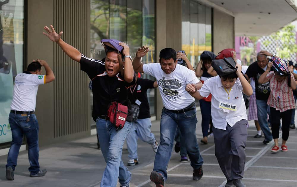 People rush to safety as they simulate a powerful earthquake during a nationwide drill at a commercial center in suburban Taguig city east of Manila, Philippines.