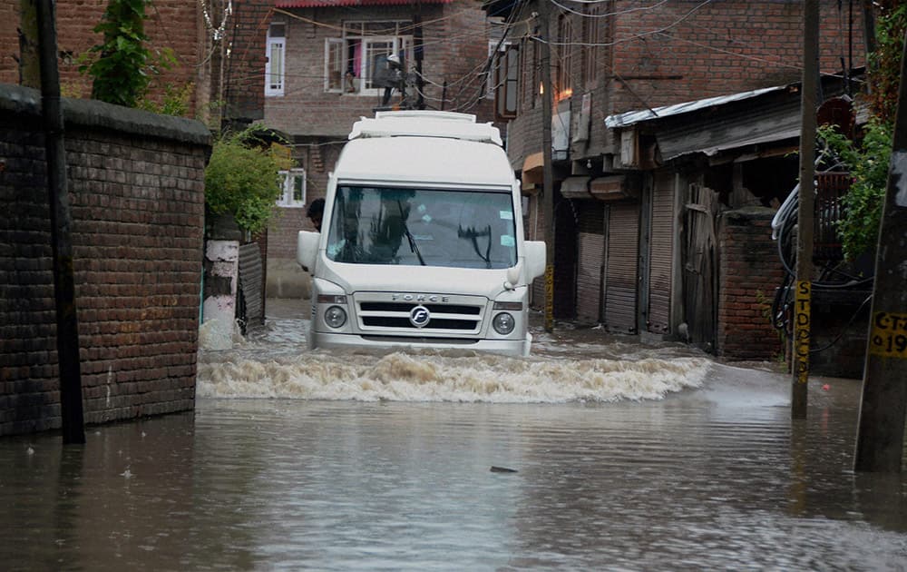 A vehicle moves through a flooded road after heavy rains in Srinagar.