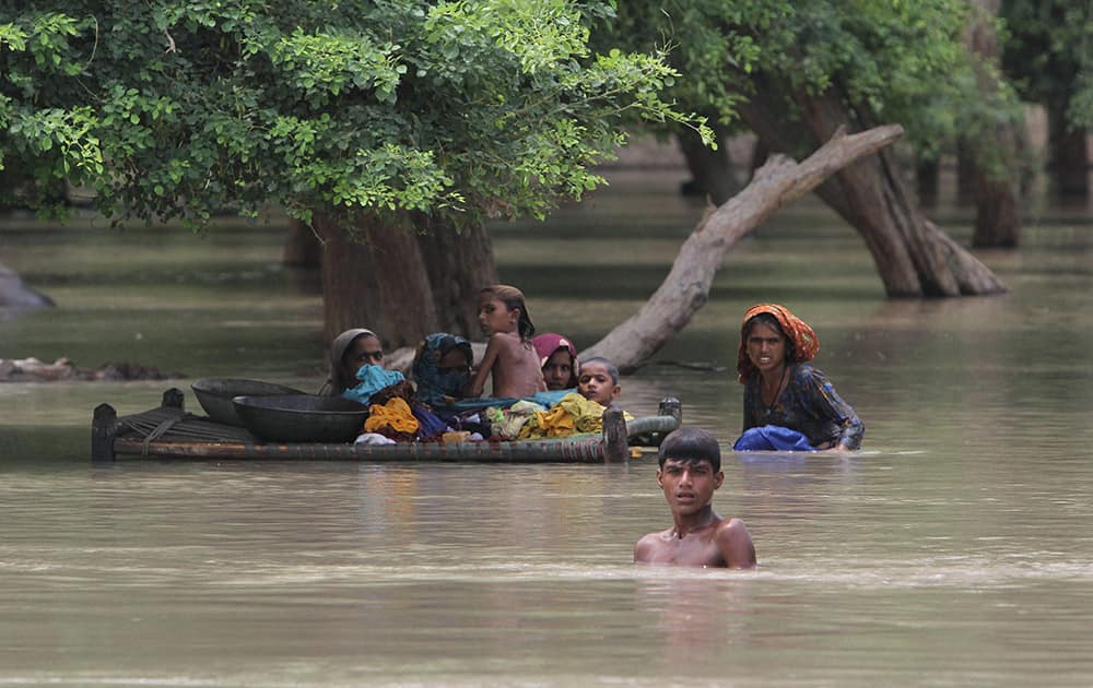 Pakistani villagers wade through floodwaters in Rajanpur, Pakistan.