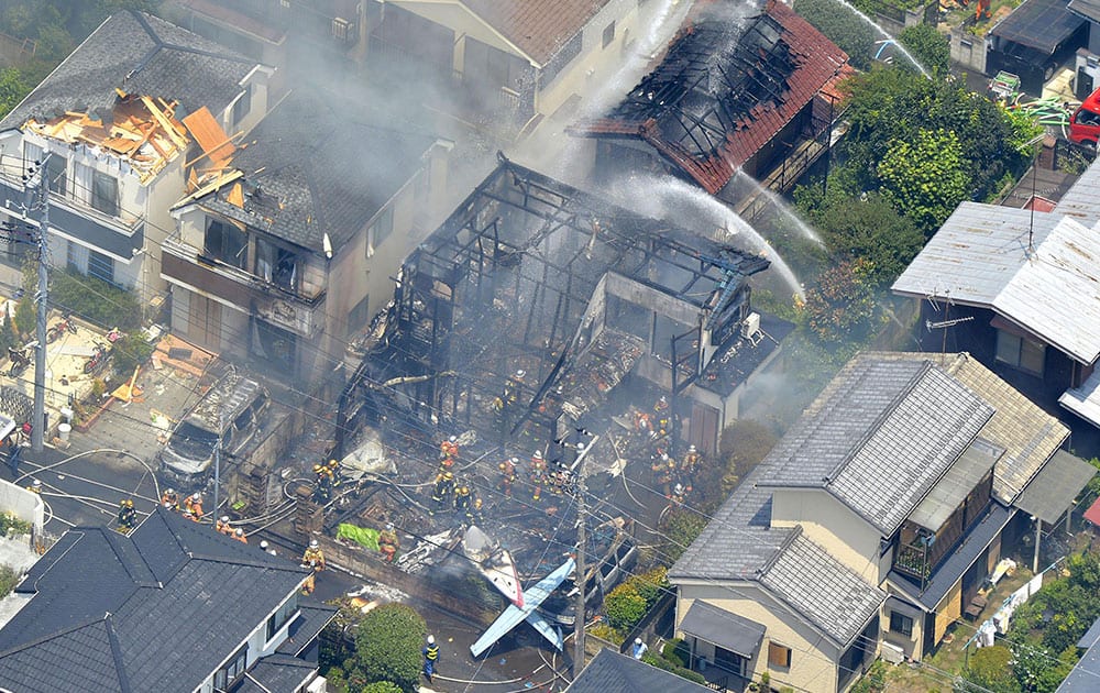 Firefighters investigate the site of a plane crash in the suburbs of Tokyo.