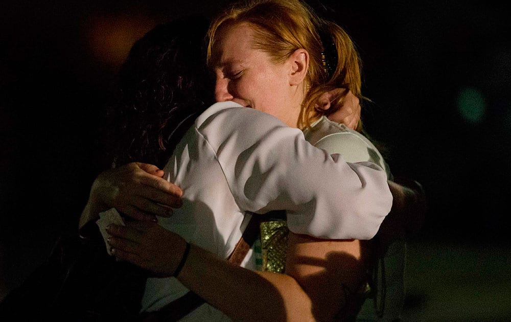 Lindsay Unruh, right embraces Brentney Harrison, both of Lafayette, during a candlelight vigil to honor the victims of Thursday night's shooting at the Grand 16 Theater, in Lafayette, La. 