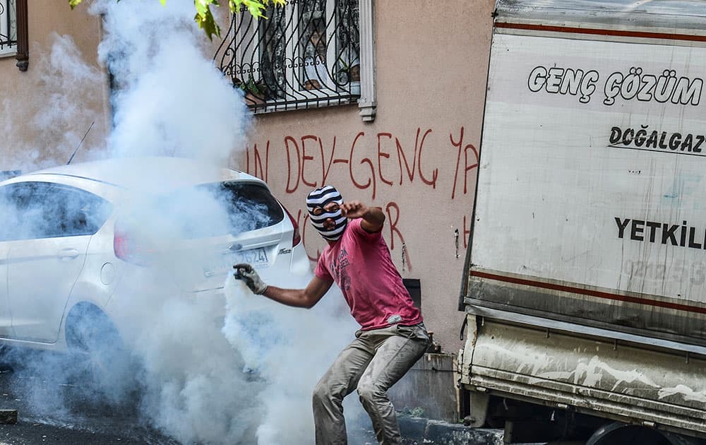 A protester runs to throw back a tear gas canister originally fired by police in Istanbul, during clashes between police and protesters denouncing the deaths of 32 people at an suicide bombing Monday in Suruc, southeastern Turkey.