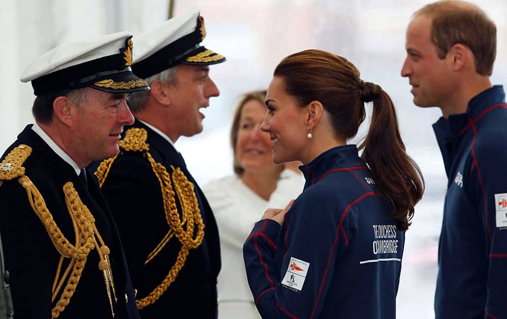 Britain's Prince William and his wife Kate, the Duchess of Cambridge, speak with dignitaries as they tour the base of Emirates Team New Zealand, for the America's Cup World Series, at the Royal Naval Dockyard in Portsmouth, England.