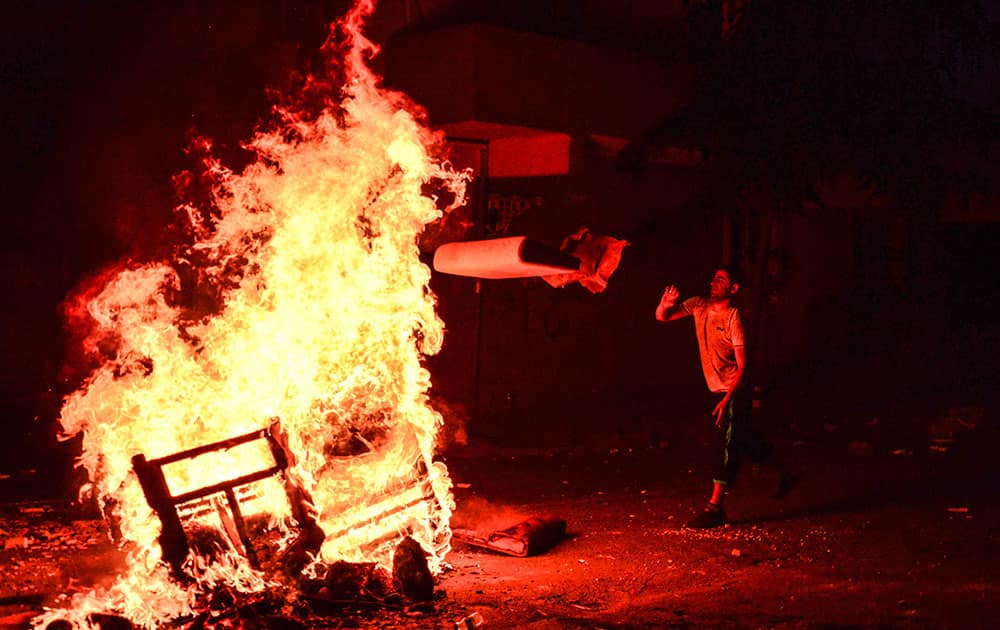 A left-wing protester throws wood into a fire lit by protesters, to help avoid tear gas used by police to disperse them, in Istanbul, during clashes between police and people protesting against Turkey's operation against Kurdish militants. 