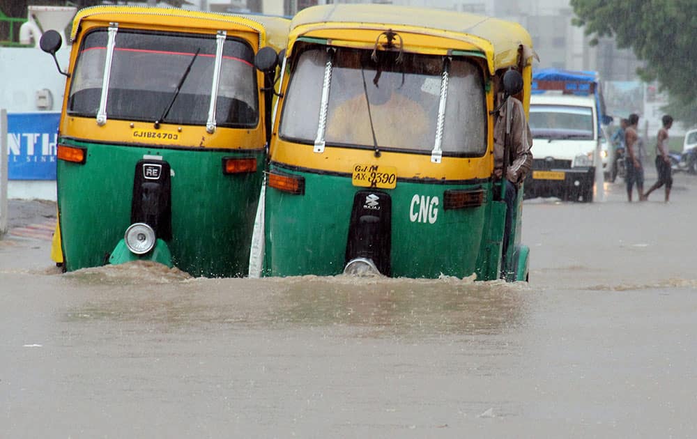 Vehicles moving through a flooded road during heavy rainfall in Ahmedabad.