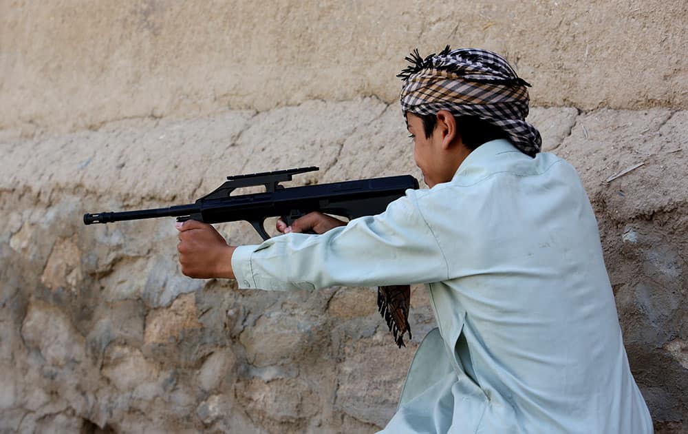 an Afghan boy plays with his friends using a toy gun, in Kabul, Afghanistan. 