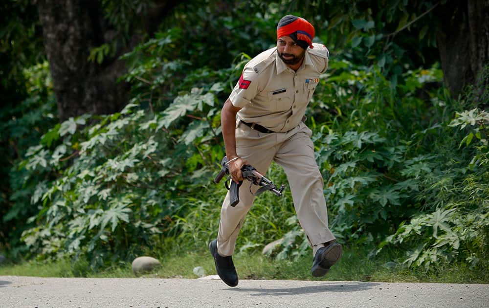 An Indian policeman takes position during a fight in the town of Dinanagar, in the northern state of Punjab, India.