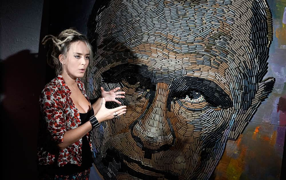 Ukrainian artist Dasha Marchenko poses next to her portrait of Russian President Vladimir Putin, made by out of cartridge cases, in the artist's studio in Kiev, Ukraine.