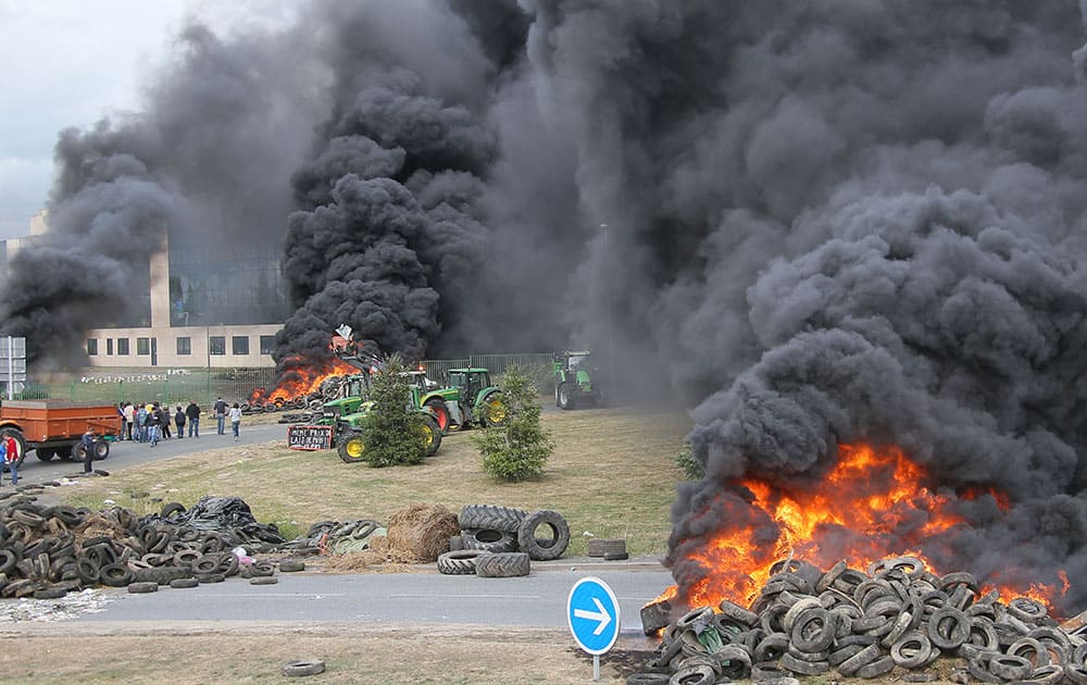 French farmers burn tyres as they gather in front of Lactalis' factory in Laval, western France in order to protest against importation of foreign meat and milk products in France.