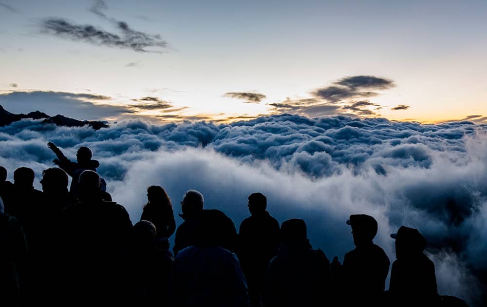 Tourists watch the sunrise above a sea of fog on Eggishorn moutain (2927 meters over sea level), in Fiesch, Switzerland.