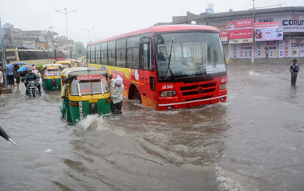 Commuters wade through a flooded road after heavy rains in Ahmedabad.