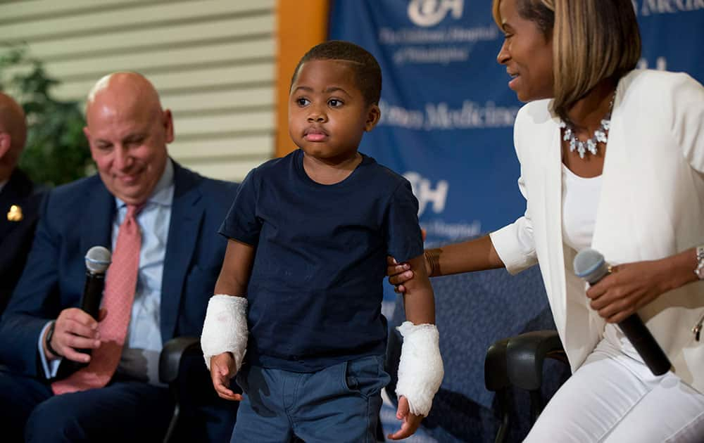 Double-hand transplant recipient eight-year-old Zion Harvey accompanied by Dr. L. Scott Levin, left, and his mother Pattie Ray, stands during a news conference at The Children’s Hospital of Philadelphia (CHOP) in Philadelphia. 