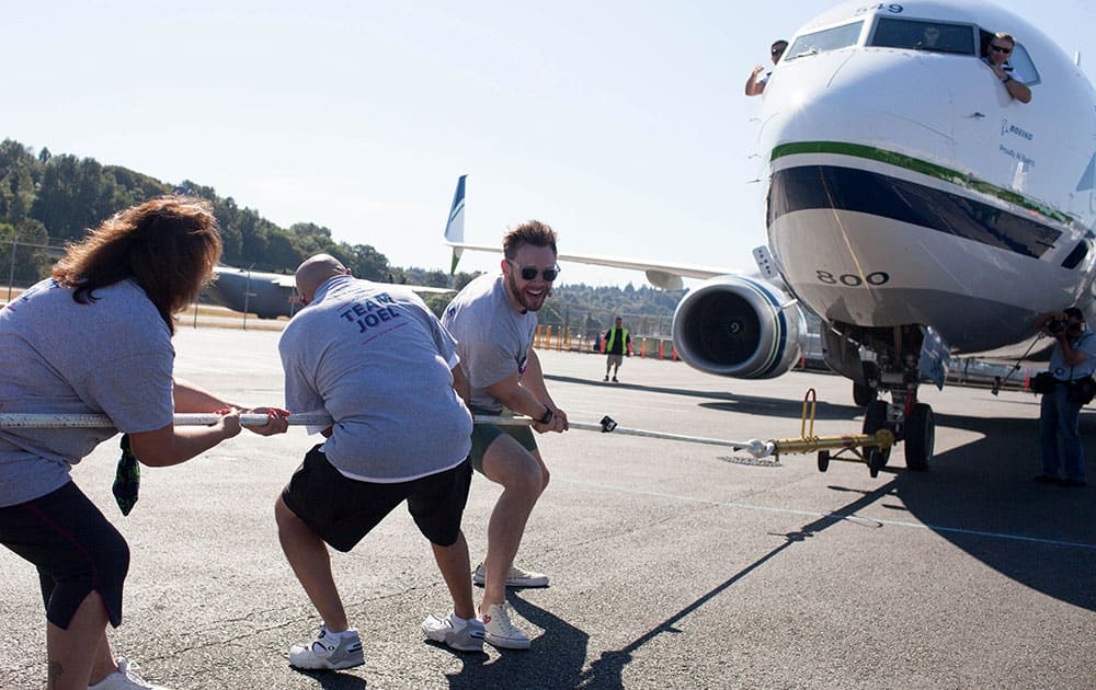 Joel McHale pulls the plane during the Alaska Airlines Plane Pull competition against Russell Wilson, benefiting Strong Against Cancer at The Museum of Flight in Seattle.