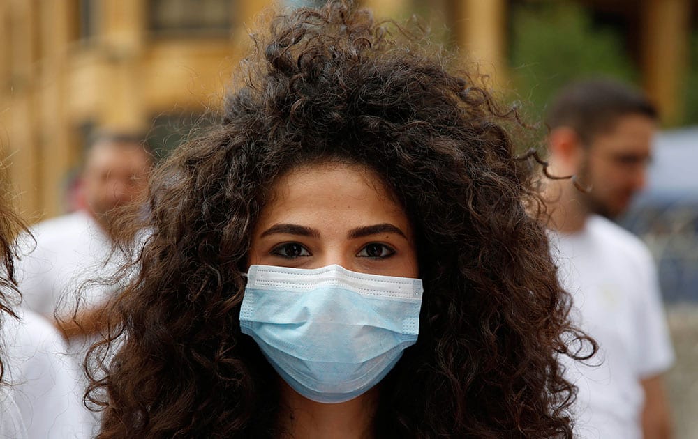 A Lebanese protester covers her mouth with a medical mask as she protests against the ongoing trash crisis, in front of the government house, in downtown Beirut, Lebanon.