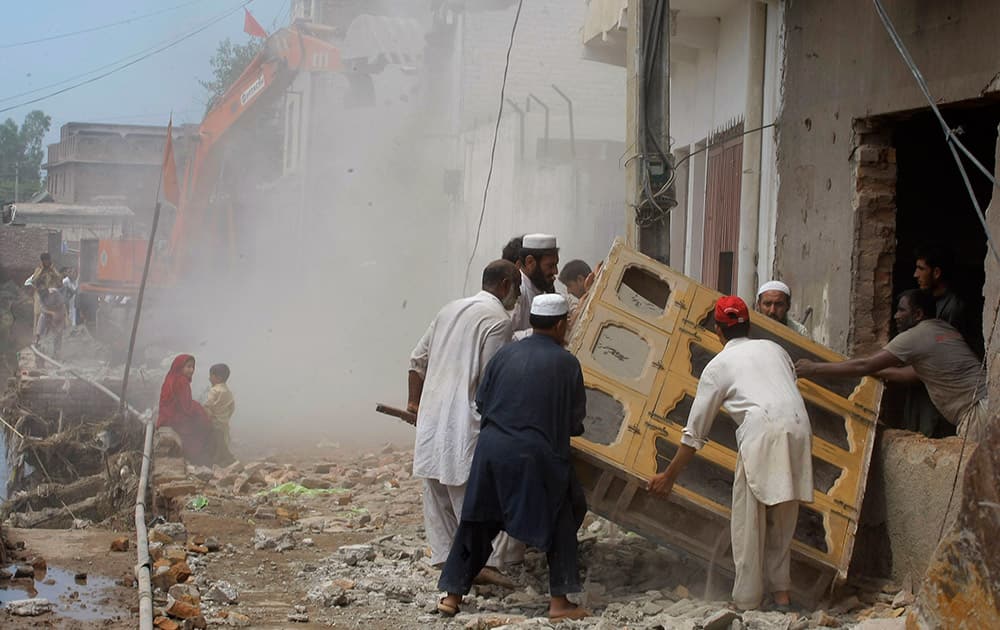 Pakistani residents remove fixtures from their house that has partially collapsed due to heavy rain in Peshawar, Pakistan.