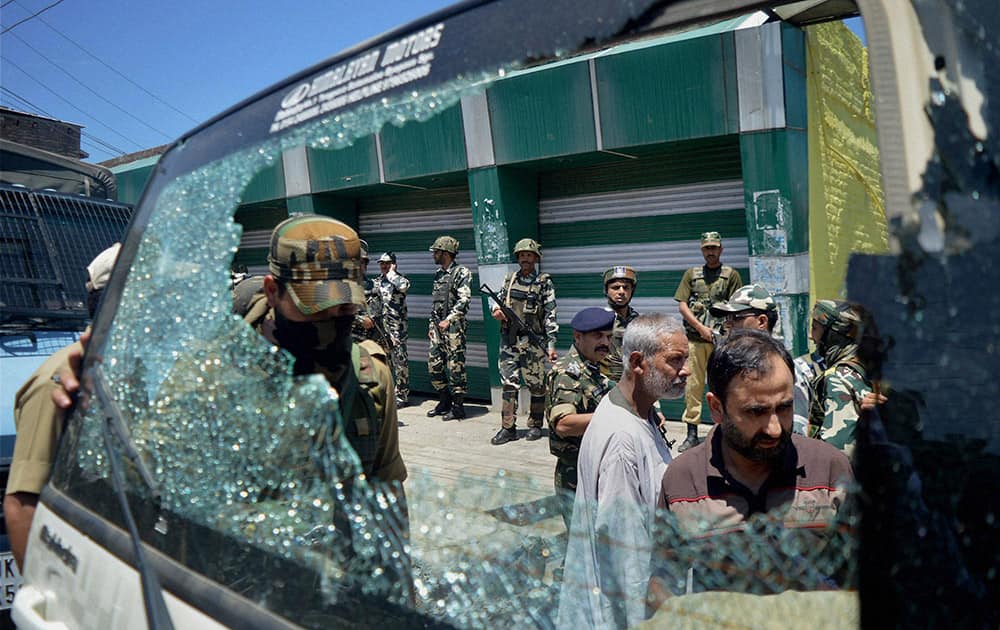 Security personnel and civilians inspecting a damaged vehicle at the site of a grenade blast at K P Road in South Kashmir’s Anantnag district.