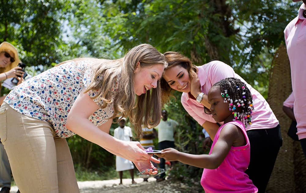 Clinton Foundation Vice Chair Chelsea Clinton, left, receives a gift from Theresa Balde, 5, during a visit to the Acceso Peanut Enterprise Corporation and Chakipi Distribution Enterprise, in Mirebalais, Haiti.