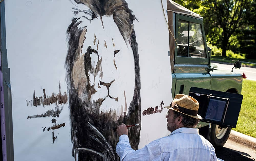 Artist Mark Balma paints a mural of Cecil, a well-known lion killed by Minnesota dentist Walter Palmer during a guided bow hunting trip in Zimbabwe, as part of a silent protest outside Palmer's office in Bloomington, Minn.