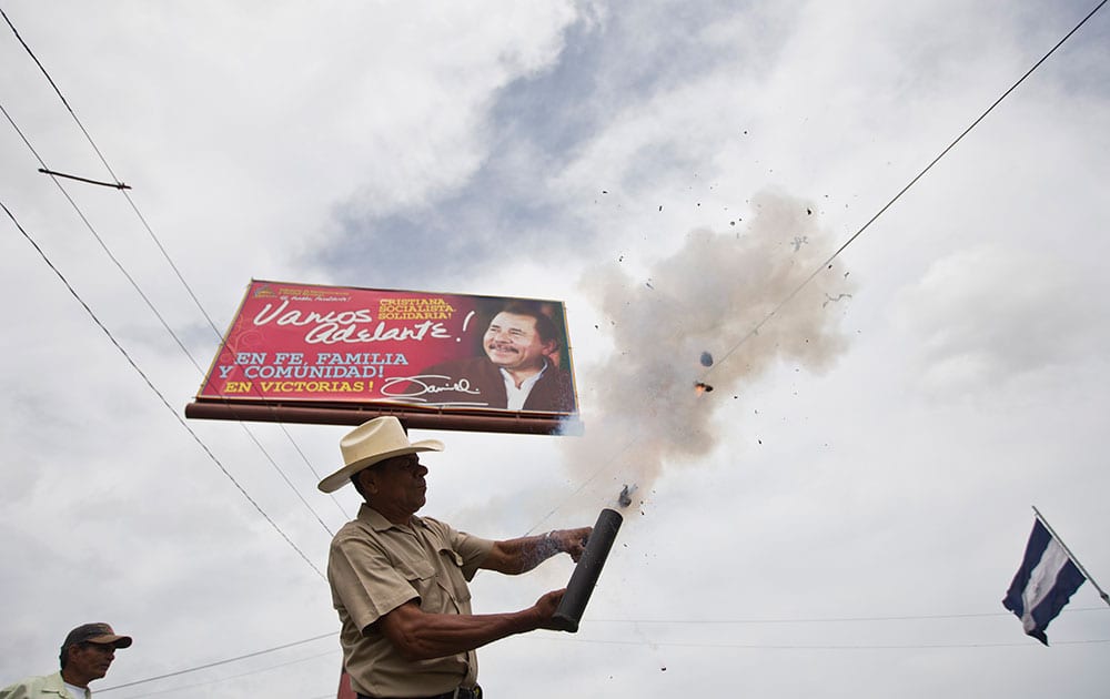 An anti-government protester fires a homemade mortar in front of a banner promoting Nicaragua's President Daniel Ortega, near the Supreme Electoral Council, during a demonstration demanding fair elections in Managua, Nicaragua.