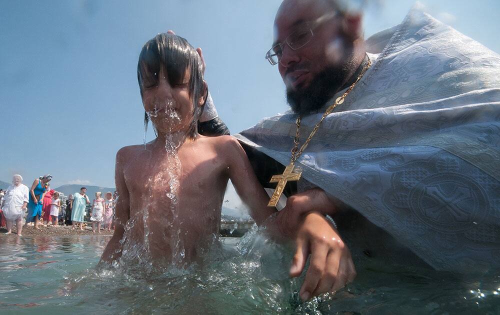 An Orthodox priest baptizes a child during a celebration a celebration of the 1000th anniversary of the death of Great Prince Vladimir in Yalta, Crimea.