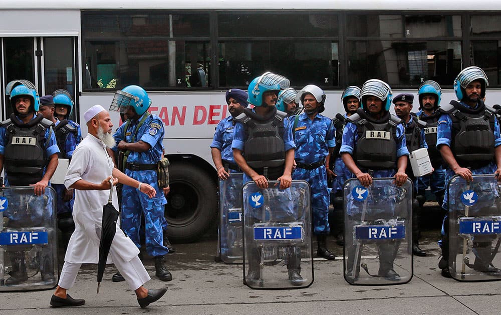 A man walks past Rapid Action Force (RAF) soldiers standing guard in the neighborhood of Yakub Abdul Razak Memon's family residence in Mumbai.