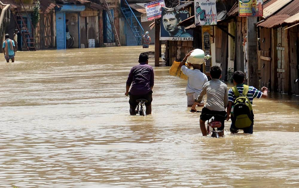 People wade through a flooded locality in West Midnapore district, West Bengal.