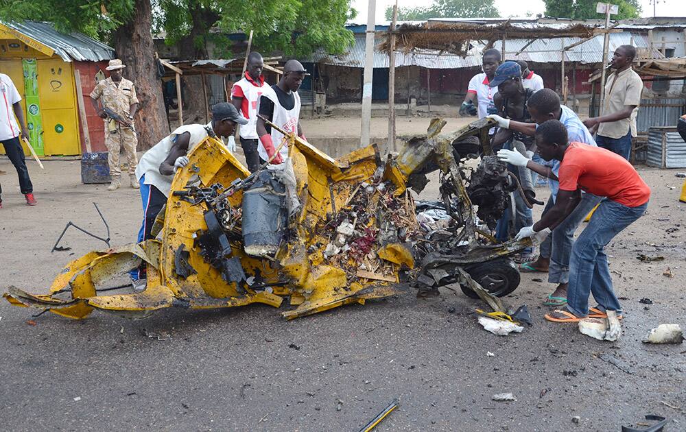 People inspect a damaged tricycle at the site of a bomb explosion in Maiduguri, Nigeria. A woman suicide bomber killed many people at a crowded market early Friday in a blast that thundered across the northeastern Nigerian city of Maiduguri, witnesses said.