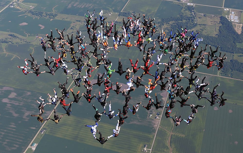 This photo provided by Gustavo Cabana, members of an international team of skydivers join hands, flying head-down to build their world record skydiving formation, over Ottawa, Ill.