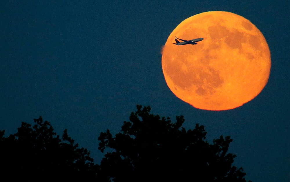 A plane ascends in front of a blue moon rising seen from Liberty State Park in Jersey City, N.J.