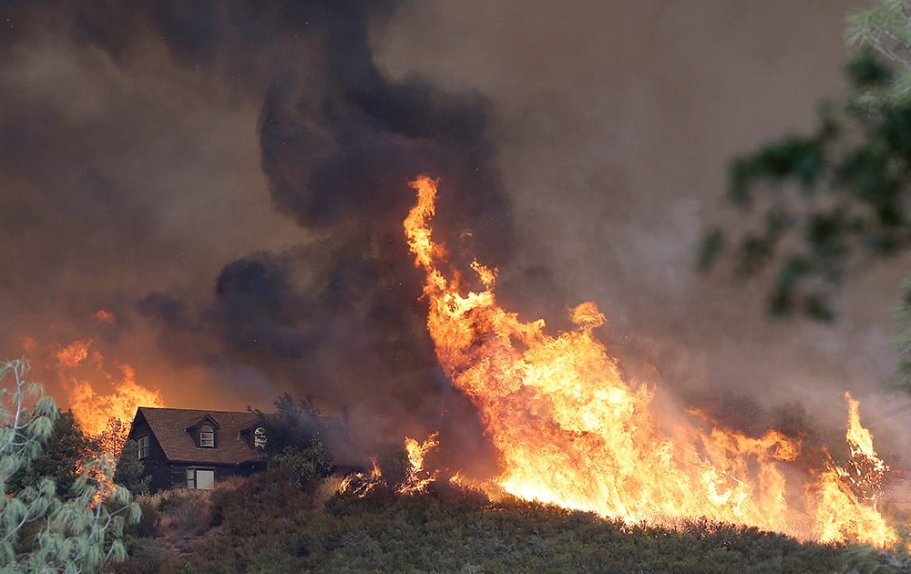 Fires approach a home near Lower Lake, Calif. A series of wildfires were intensified by dry vegetation, triple-digit temperatures and gusting winds.