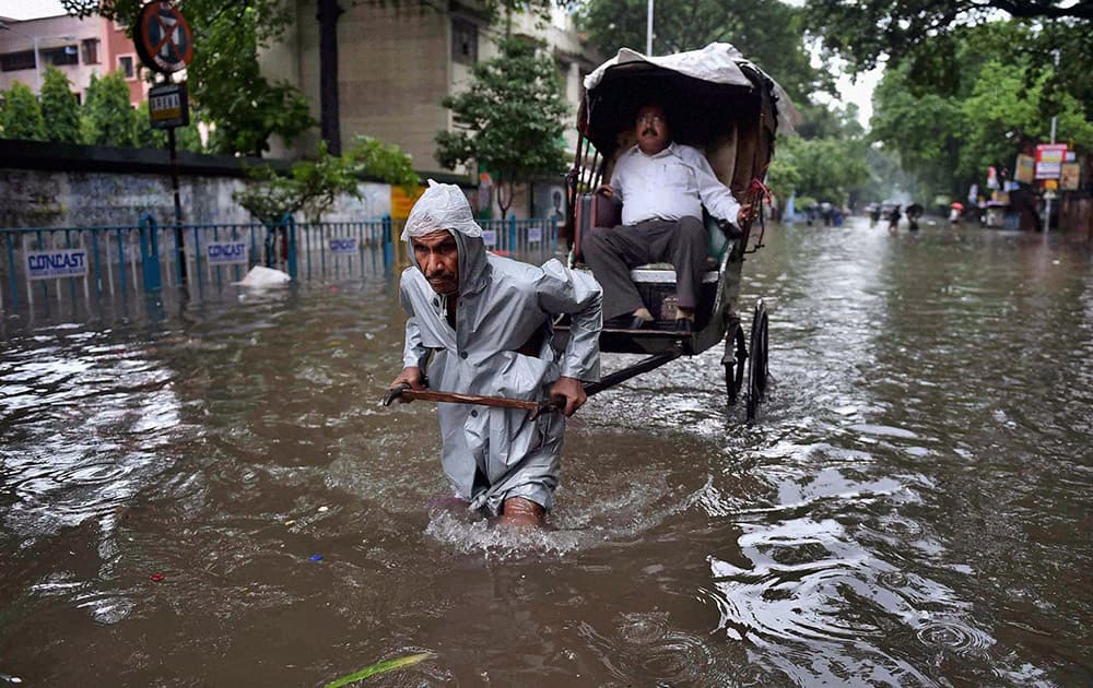 A hand rickshaw puller transports a man to his destination through a water logged street after heavy rains in Kolkata.