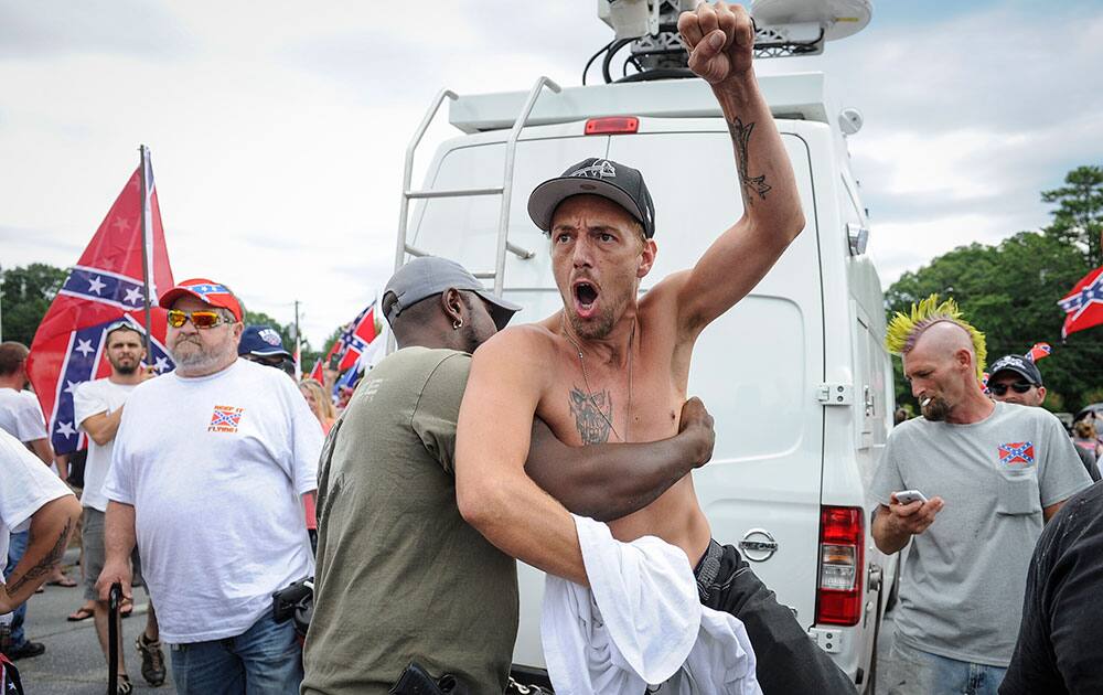 Confederate flag supporter Jerry Gray of Conyers, Ga., is held back by a fellow supporter as he yells at Ku Klux Klan members to go home, while he and others protest what they believe is an attack on their Southern heritage during a rally at Stone Mountain Park in Stone Mountain, Ga.