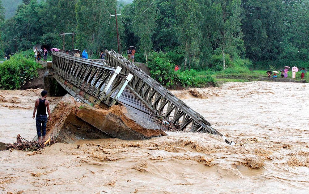 People look at the bridge which is washed away by the flood water in Thoubal District in Manipur.