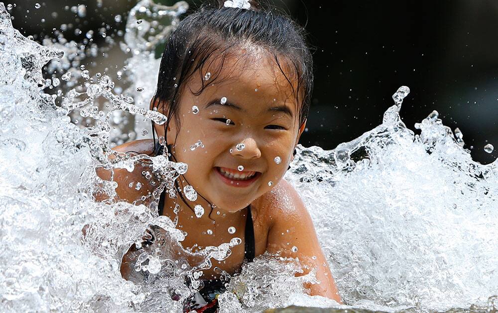 A girl plays in the water fountain at Asuka park in Tokyo.