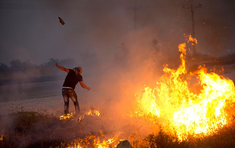 A Palestinian demonstrator kicks a tear gas canister fired by Israeli soldiers during clashes at the entrance to Duma village near the West Bank city of Nablus.