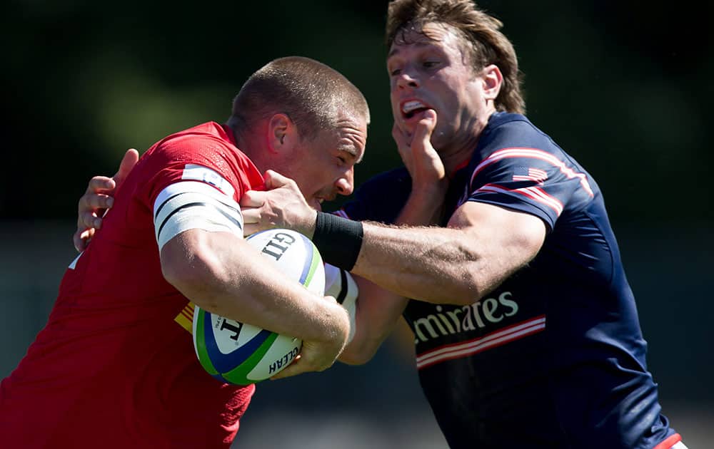 Canada's Nick Blevins, left, fights off The United States' Blaine Scully to score a try during the second half of a Pacific Nations Cup fifth place rugby match in Burnaby, British Columbia.