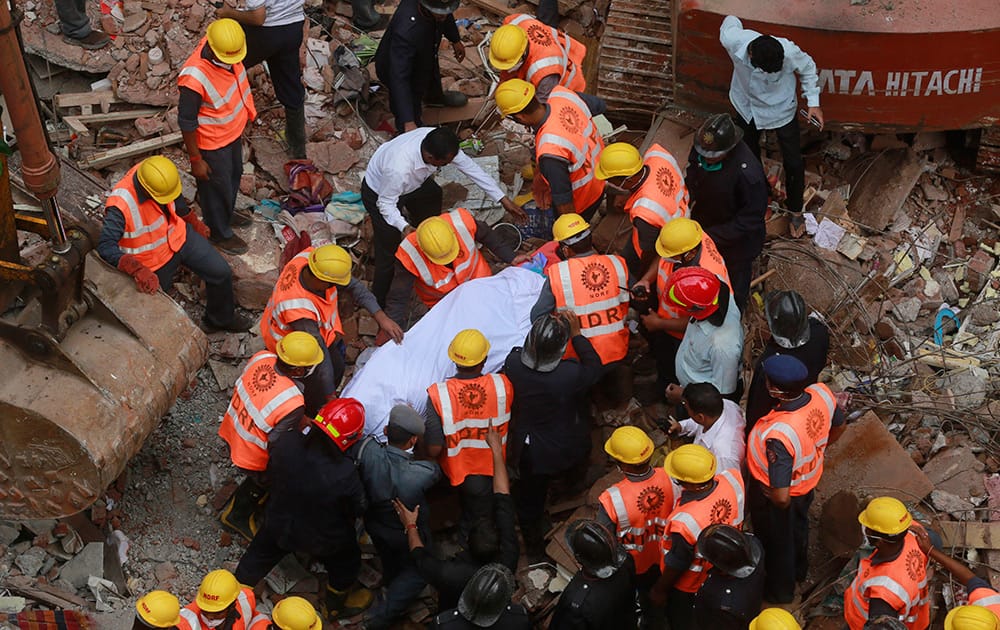 Rescue workers carry the body of a victim at the site of building collapse in Thane, Mumbai. According to an official the building was more than 50 years old and had been damaged by the rain.