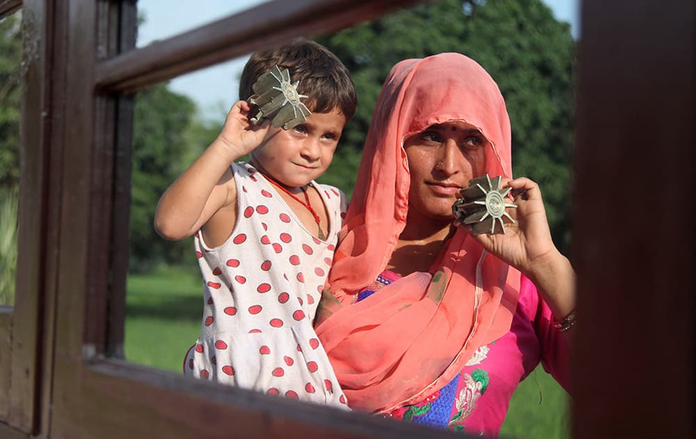 A woman and a child display mortar shells allegedly fired from the Pakistan side at a residential area near the India-Pakistan international border at Kanachack village in Pargwal sector, about 25 kilometers (16 miles) from Jammu.