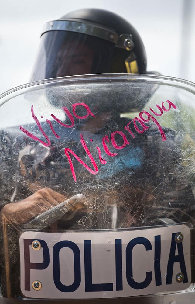 A riot police officer holds his shield after it was scribbled on with lipstick with the message in Spanish 