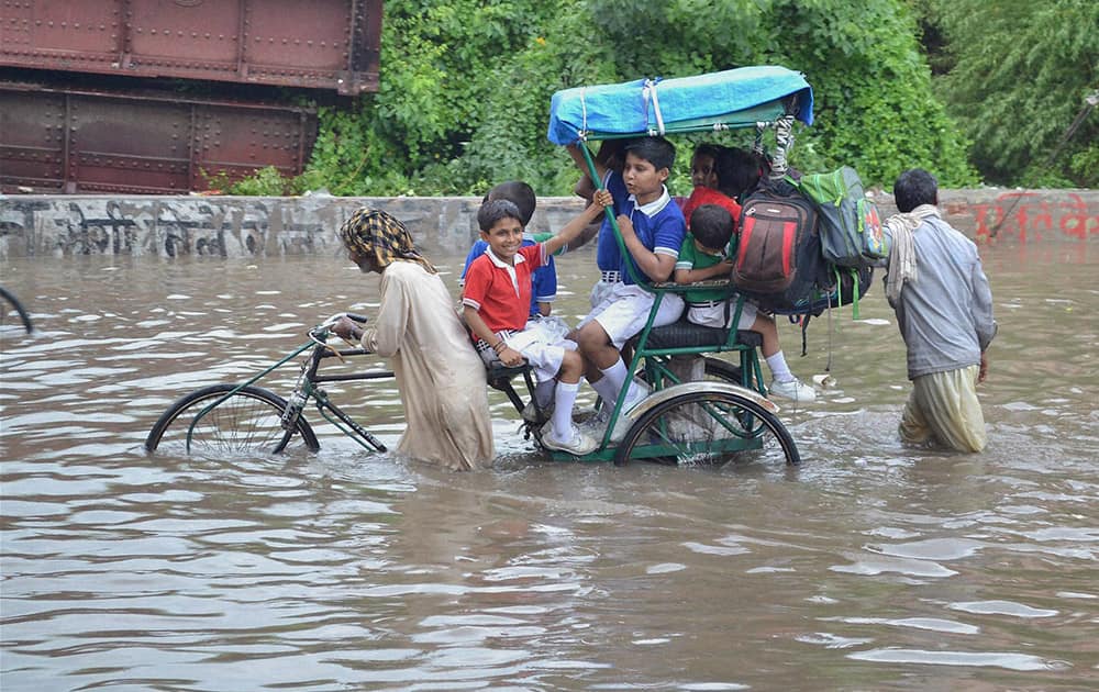 School children move through a flooded street after heavy rainfall in Mathura.