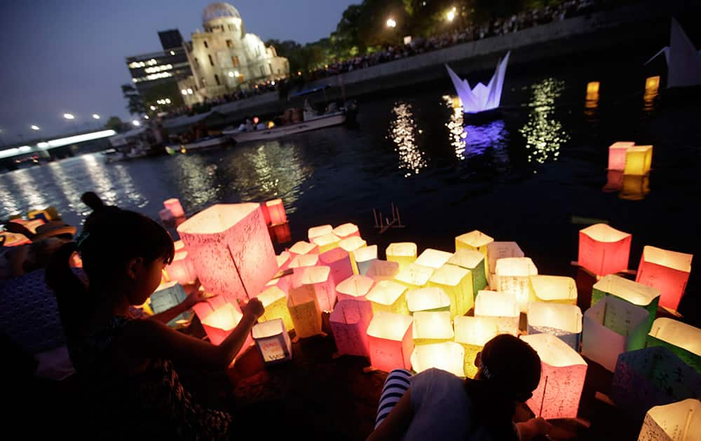 Children offer prayers as after releasing paper lanterns to the Motoyasu River where hundreds of thousands of atomic bombing victims died with the backdrop of the Atomic Bomb Dome in Hiroshima, western Japan. Japan marked the 70th anniversary Thursday of the atomic bombing of Hiroshima.