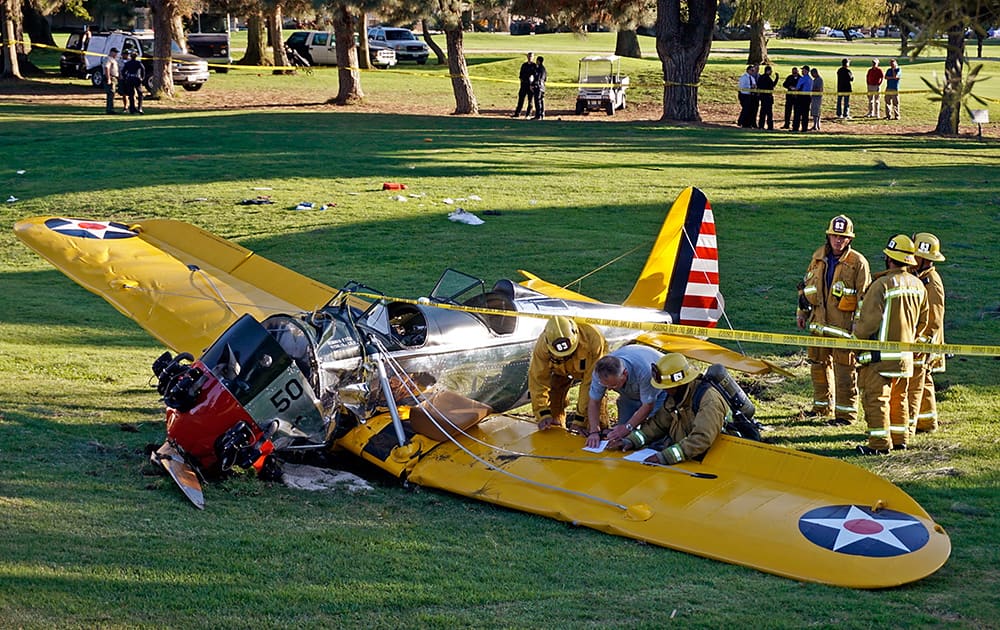 Officials work on the scene of a vintage airplane that crash-landed on the Penmar Golf Course in the Venice area of Los Angeles.