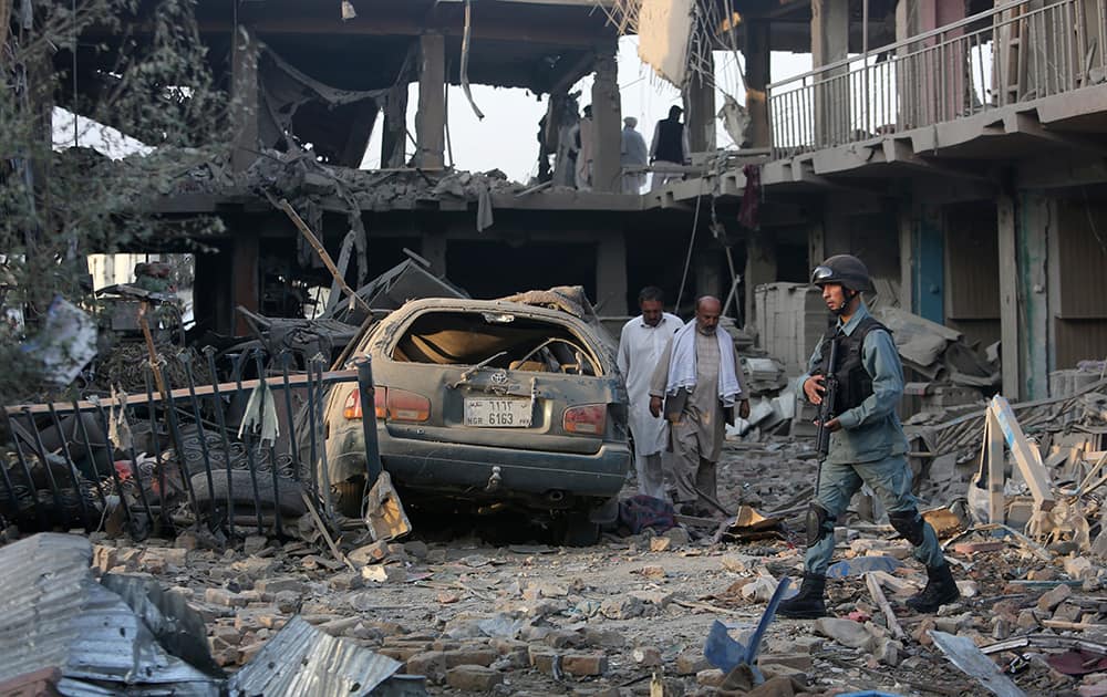 An Afghan police officer, walks at the site of a car bomb attack in Kabul, Afghanistan. A bomb hidden in a truck exploded in the center of the Afghan capital. Police chief Abdul Rahman Rahimi said the pre-dawn blast was near a Defense Ministry compound, but that all of the victims were civilians, including women and children.