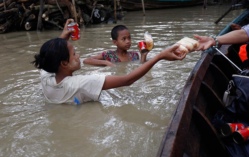 Residents standing in floodwaters receive food from private donors in Nyaung Tone, in the Irrawaddy Delta, southwest of Yangon, Myanmar.